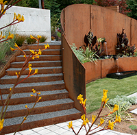 The spiral stair brings the visitor to the inner garden space, where the custom spa and spilling water feature brings inward focus to the space. The steel wall was acid washed to accelerate the corrosion process. The cannas and artemesia, chosen for their heat tolerance, were planted just one month prior to this shot. Anigozanthos in the foreground container.