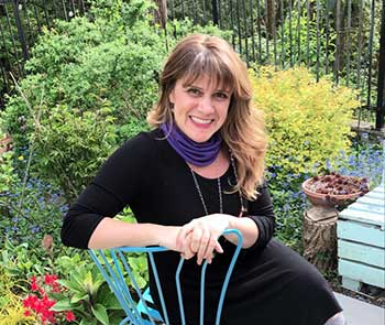 Heidi Coffee Skagen, designer and owner of Coffee Grounds Garden Design, sits on the patio in her garden surrounded by plants.